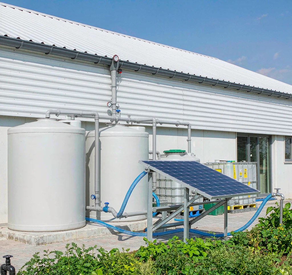 Rainwater harvesting tanks with a solar water pump and photovoltaic panel supplying garden irrigation